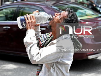 A rickshaw driver is drinking water from a roadside water pipeline during high temperature weather in Dhaka, Bangladesh, on June 24, 2024 (