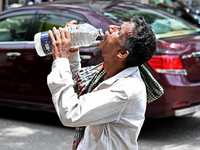 A rickshaw driver is drinking water from a roadside water pipeline during high temperature weather in Dhaka, Bangladesh, on June 24, 2024 (