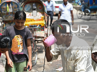 A rickshaw driver is drinking water from a roadside water pipeline during high temperature weather in Dhaka, Bangladesh, on June 24, 2024 (