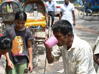 A rickshaw driver is drinking water from a roadside water pipeline during high temperature weather in Dhaka, Bangladesh, on June 24, 2024 (