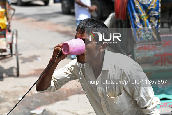 A rickshaw driver is drinking water from a roadside water pipeline during high temperature weather in Dhaka, Bangladesh, on June 24, 2024 