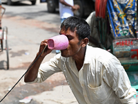 A rickshaw driver is drinking water from a roadside water pipeline during high temperature weather in Dhaka, Bangladesh, on June 24, 2024 (