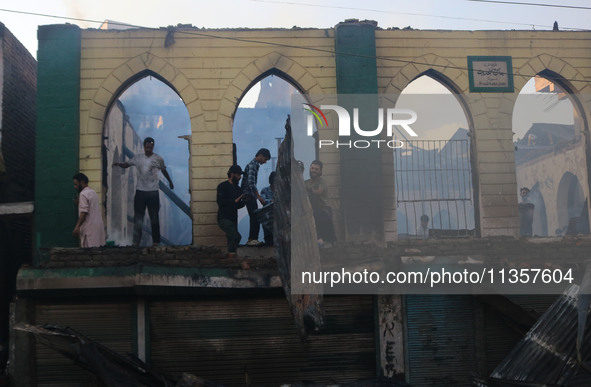 Civilians are working to extinguish a fire in Srinagar, Jammu and Kashmir, on June 24, 2024. A mosque and some buildings are being damaged i...