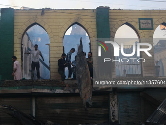 Civilians are working to extinguish a fire in Srinagar, Jammu and Kashmir, on June 24, 2024. A mosque and some buildings are being damaged i...