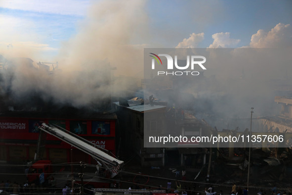 Indian firefighters and civilians are working to extinguish a fire in Srinagar, Jammu and Kashmir, on June 24, 2024. A mosque and some build...