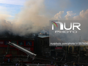 Indian firefighters and civilians are working to extinguish a fire in Srinagar, Jammu and Kashmir, on June 24, 2024. A mosque and some build...