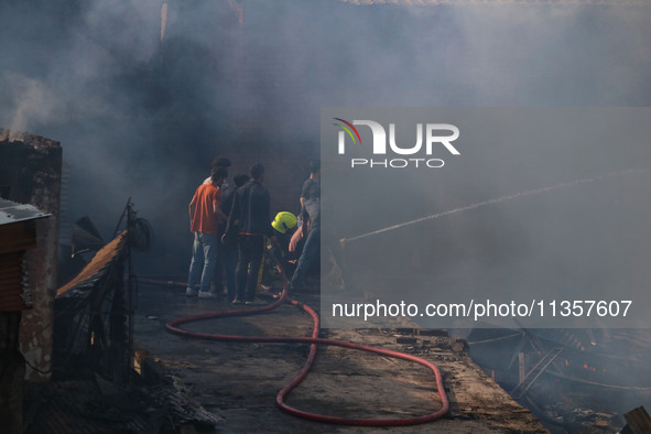 Indian firefighters and civilians are working to extinguish a fire in Srinagar, Jammu and Kashmir, on June 24, 2024. A mosque and some build...