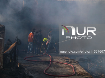 Indian firefighters and civilians are working to extinguish a fire in Srinagar, Jammu and Kashmir, on June 24, 2024. A mosque and some build...