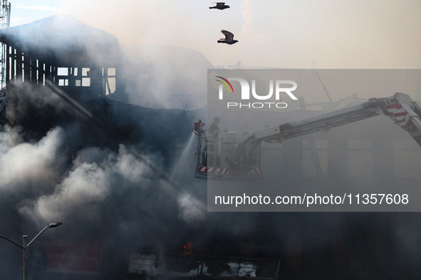 An Indian firefighter is working to extinguish a fire in Srinagar, Jammu and Kashmir, on June 24, 2024. A mosque and some buildings are bein...