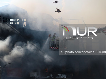 An Indian firefighter is working to extinguish a fire in Srinagar, Jammu and Kashmir, on June 24, 2024. A mosque and some buildings are bein...