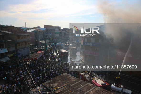 People are watching from a distance as firefighters and civilians are working to extinguish a fire in Srinagar, Jammu and Kashmir, on June 2...