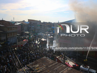 People are watching from a distance as firefighters and civilians are working to extinguish a fire in Srinagar, Jammu and Kashmir, on June 2...