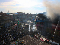 People are watching from a distance as firefighters and civilians are working to extinguish a fire in Srinagar, Jammu and Kashmir, on June 2...