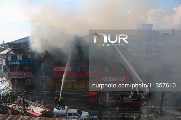 Indian firefighters and civilians are working to extinguish a fire in Srinagar, Jammu and Kashmir, on June 24, 2024. A mosque and some build...