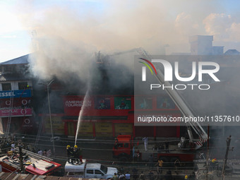 Indian firefighters and civilians are working to extinguish a fire in Srinagar, Jammu and Kashmir, on June 24, 2024. A mosque and some build...