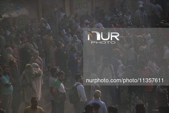 People are watching from a distance as firefighters and civilians are working to extinguish a fire in Srinagar, Jammu and Kashmir, on June 2...