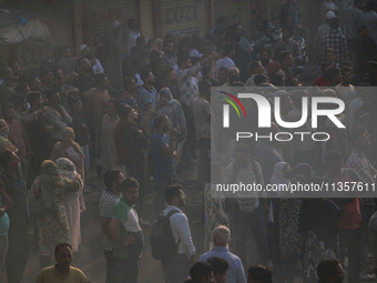 People are watching from a distance as firefighters and civilians are working to extinguish a fire in Srinagar, Jammu and Kashmir, on June 2...