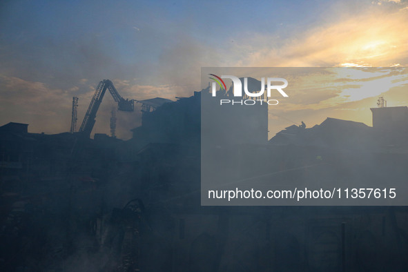 Indian firefighters and civilians are working to extinguish a fire in Srinagar, Jammu and Kashmir, on June 24, 2024. A mosque and some build...