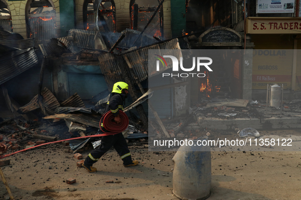 A firefighter is preparing to douse the fire in a congested neighborhood in Old City, Srinagar, Indian Administered Kashmir, on June 24, 202...