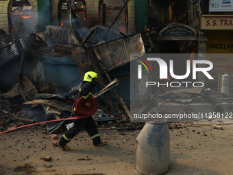 A firefighter is preparing to douse the fire in a congested neighborhood in Old City, Srinagar, Indian Administered Kashmir, on June 24, 202...