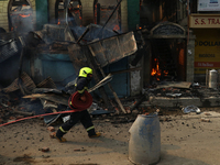 A firefighter is preparing to douse the fire in a congested neighborhood in Old City, Srinagar, Indian Administered Kashmir, on June 24, 202...