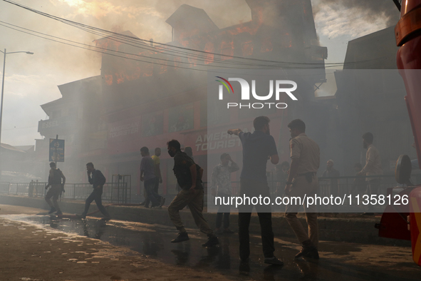 Local people are running to get help to douse the fire in a congested neighborhood in Old City Srinagar, Indian Administered Kashmir, on Jun...