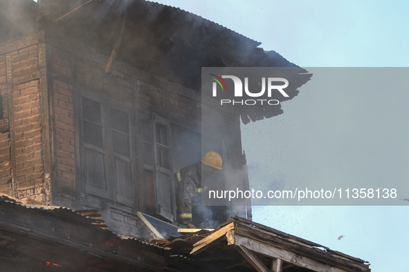 A firefighter is trying to escape from a burning house in a congested neighborhood in Old City, Srinagar, Indian Administered Kashmir, on Ju...