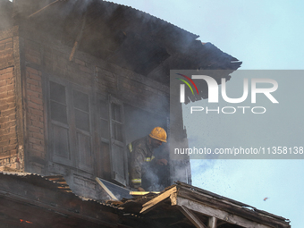 A firefighter is trying to escape from a burning house in a congested neighborhood in Old City, Srinagar, Indian Administered Kashmir, on Ju...