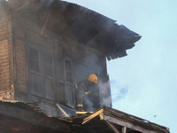 A firefighter is trying to escape from a burning house in a congested neighborhood in Old City, Srinagar, Indian Administered Kashmir, on Ju...