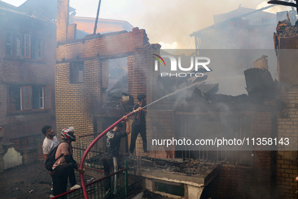 People are trying to douse the fire in a congested neighborhood in Old City Srinagar, Indian Administered Kashmir, on June 24, 2024. Several...