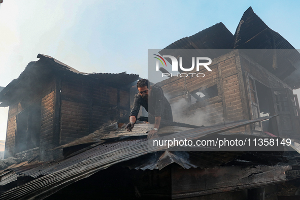 A man is clearing the debris from a damaged residential house after fire engulfs a congested neighborhood in Old City Srinagar, Indian Admin...