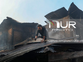 A man is clearing the debris from a damaged residential house after fire engulfs a congested neighborhood in Old City Srinagar, Indian Admin...