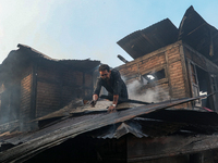 A man is clearing the debris from a damaged residential house after fire engulfs a congested neighborhood in Old City Srinagar, Indian Admin...