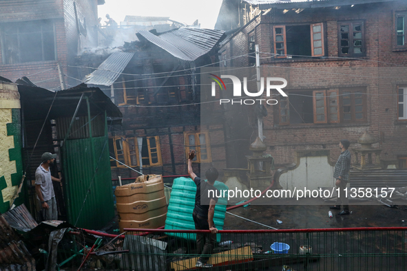 A residential house is collapsing as the fire is engulfing a congested neighborhood in Old City Srinagar, Indian Administered Kashmir, on Ju...