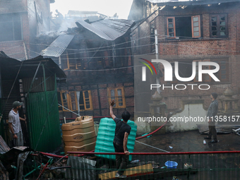 A residential house is collapsing as the fire is engulfing a congested neighborhood in Old City Srinagar, Indian Administered Kashmir, on Ju...