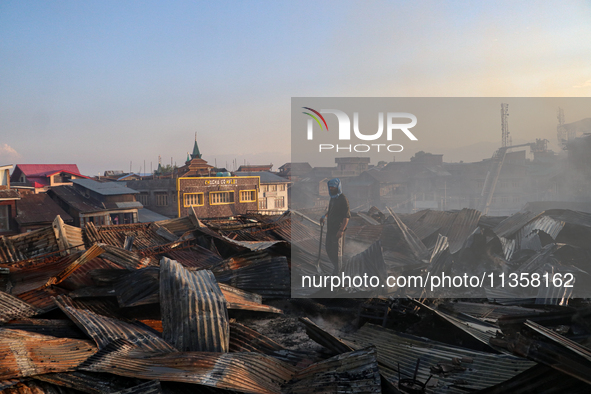 People are clearing the debris inside a damaged building after a fire engulfed a congested neighborhood in Old City Srinagar, Indian Adminis...