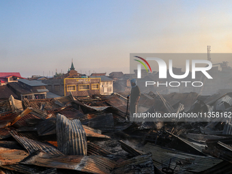 People are clearing the debris inside a damaged building after a fire engulfed a congested neighborhood in Old City Srinagar, Indian Adminis...