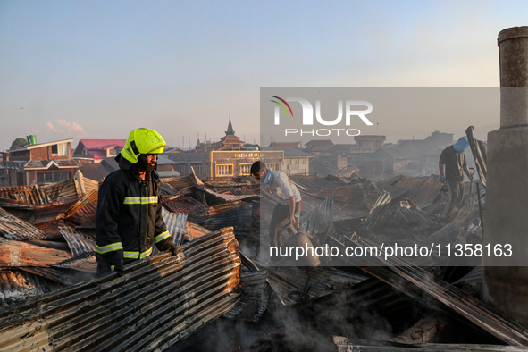 People are clearing the debris inside a damaged building after a fire engulfed a congested neighborhood in Old City Srinagar, Indian Adminis...