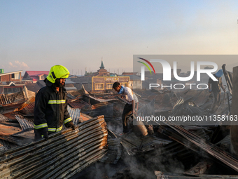 People are clearing the debris inside a damaged building after a fire engulfed a congested neighborhood in Old City Srinagar, Indian Adminis...