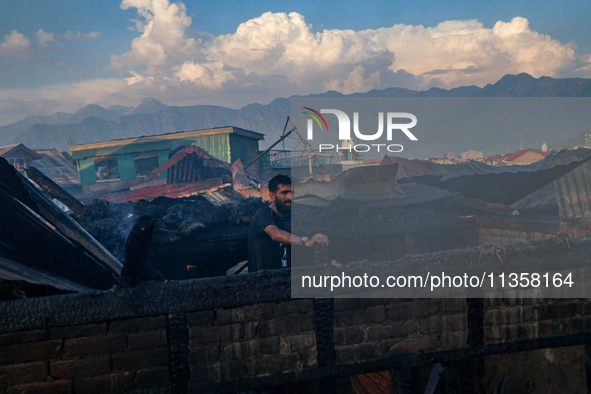 A man is standing atop a damaged building after a fire engulfed a congested neighborhood in Old City Srinagar, Indian Administered Kashmir,...