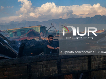 A man is standing atop a damaged building after a fire engulfed a congested neighborhood in Old City Srinagar, Indian Administered Kashmir,...