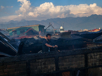 A man is standing atop a damaged building after a fire engulfed a congested neighborhood in Old City Srinagar, Indian Administered Kashmir,...