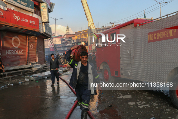 A firefighter is carrying a water hose after a fire engulfed a congested neighborhood in Old City Srinagar, Indian Administered Kashmir, on...