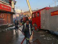 A firefighter is carrying a water hose after a fire engulfed a congested neighborhood in Old City Srinagar, Indian Administered Kashmir, on...