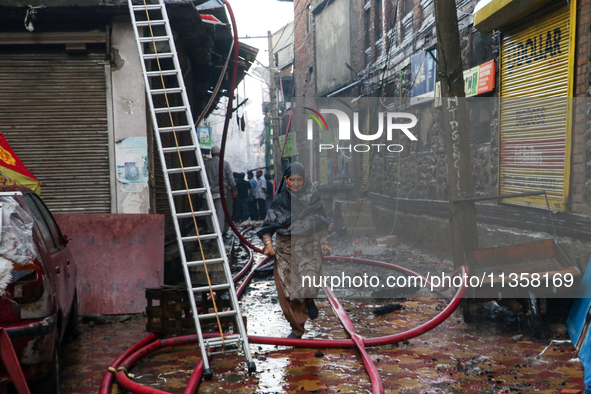 A woman is running for safety after a fire is engulfing a congested neighborhood in Old City Srinagar, Indian Administered Kashmir, on June...