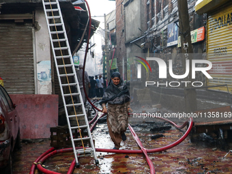 A woman is running for safety after a fire is engulfing a congested neighborhood in Old City Srinagar, Indian Administered Kashmir, on June...