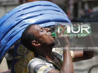 A thirsty rickshaw puller is drinking water to get relief on a hot summer day in Dhaka, Bangladesh, on June 24, 2024. (