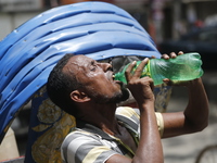 A thirsty rickshaw puller is drinking water to get relief on a hot summer day in Dhaka, Bangladesh, on June 24, 2024. (