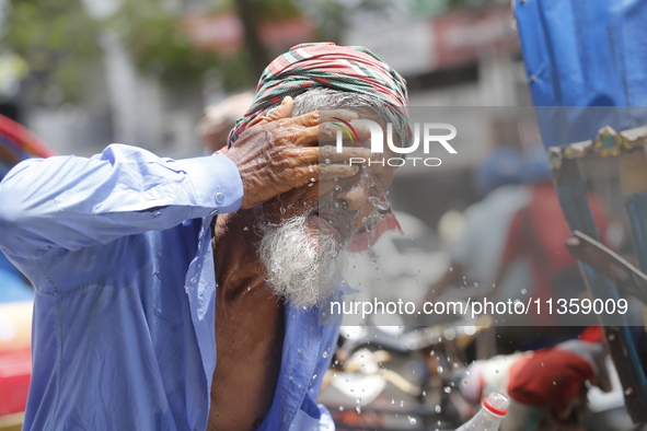 A rickshaw puller is splashing water on his face to get relief on a hot summer day in Dhaka, Bangladesh, on June 24, 2024. 