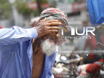 A rickshaw puller is splashing water on his face to get relief on a hot summer day in Dhaka, Bangladesh, on June 24, 2024. (